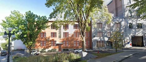 Un edificio de varios pisos con fachada de ladrillo, ventanas grandes y un hidrante en la acera.