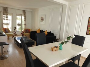 A modern living room with a dining area, featuring a white table, black chairs, and a sofa with colorful cushions. - Stylish home for your vacation (Agadir)