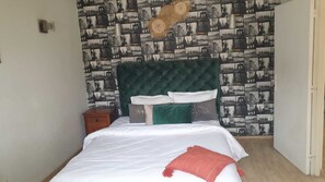 A bedroom with a bed, pillows, a nightstand, and a wall with a cityscape wallpaper. - Stylish home for your vacation (Agadir)