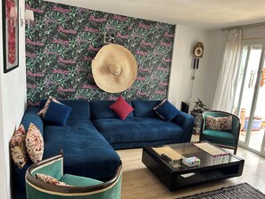 A living room with a blue sofa, a round table, and a green armchair. - Stylish home for your vacation (Agadir)