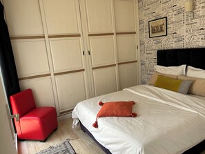 A bedroom with a bed, a red chair, a patterned rug, and a wall with motivational quotes. - Stylish home for your vacation (Agadir)