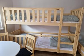 Ein Etagenbett mit Holzrahmen, ein weißer Tisch und ein Stuhl.