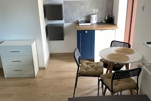 Eine kleine Küche mit Essbereich, einem weißen Schrank und einer blauen Tür.