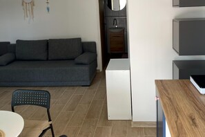 A modern living room with a grey sofa, a small table, and a chair. - Room for 4 people with kitchenette (Sarbinowo)