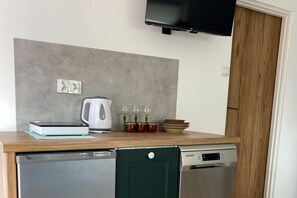 Une cuisine compacte équipée d’un lave-vaisselle, d’un four à micro-ondes, d’une bouilloire et d’une pile d’assiettes.