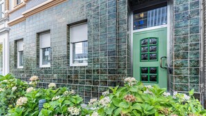 A building facade with a green door, multiple windows, and a tiled exterior. - Room 'Einzelzimmer Mit Bad' with Balcony and Wi-Fi (Düsseldorf)