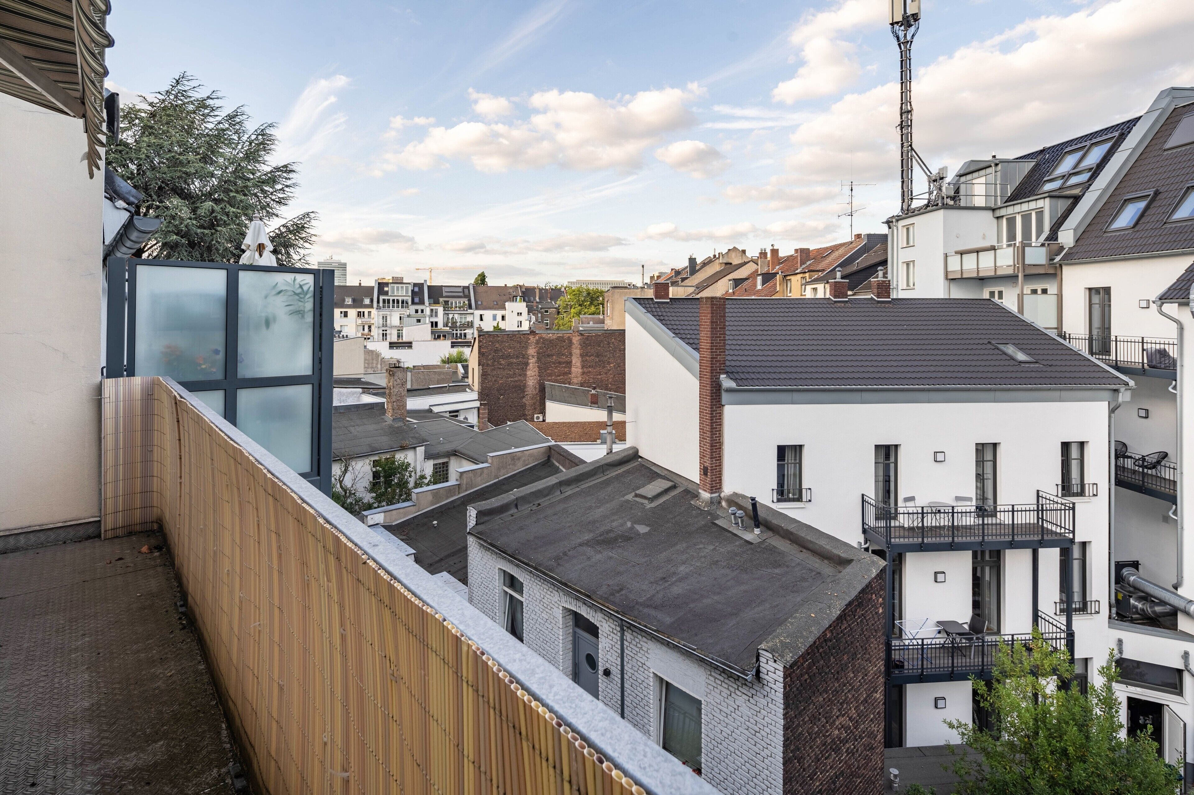 En boligbygning med moderne arkitektur, der har en balkon med gelænder af træ og glas.