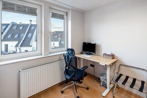 A small office space with a desk, chair, computer, and radiator. - Room 'Einzelzimmer Mit Dusche' with Balcony (Düsseldorf)
