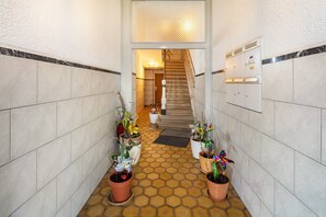 A hallway with tiled walls, a tiled floor, and a staircase leading to an upper level. - Room 'Einzelzimmer Mit Dusche' with Balcony (Düsseldorf)