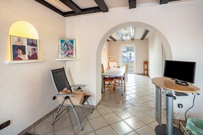 Una habitación con una mesa de comedor, sillas, un televisor y cuadros en la pared.