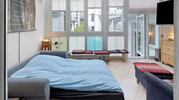 A modern bedroom with a large bed, a sofa, a small table, and a TV.