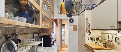 Une cuisine équipée d’un porte-ustensiles suspendu, d’une horloge et de divers accessoires de cuisine.