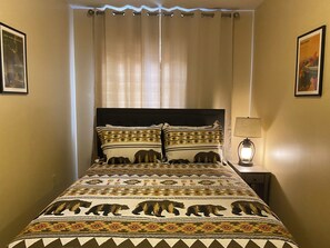 A bed with a patterned blanket, a headboard, and a bedside lamp. - Island Street Loft - downtown convenience with proximity to local attractions! (Bryson City)