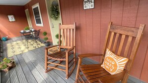 A wooden porch with two rocking chairs, a small table, and potted plants. - Island Street Loft - downtown convenience with proximity to local attractions! (Bryson City)