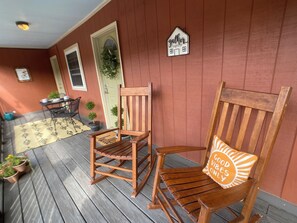 Eine hölzerne Veranda mit zwei Schaukelstühlen, einem kleinen Tisch und Topfpflanzen.