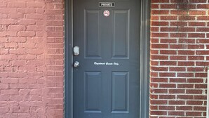 A dark-colored door with a 'PRIVATE' sign and a 'Registered Guests Only' sign, a doormat, and a partial view of a brick wall. - Island Street Loft - downtown convenience with proximity to local attractions! (Bryson City)