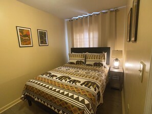 Ein Schlafzimmer mit einem Bett, einem Nachttisch, einer Lampe und zwei gerahmten Bildern an der Wand.