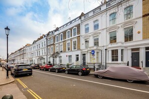 A row of white terraced houses with a street in front. - Spacious Chelsea Apartment | 3 Bedrooms | Roof Terrace (London)