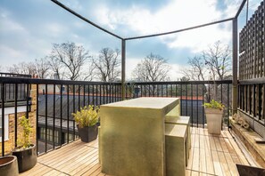 Ein Balkon mit Holzboden, Metallgeländer und Topfpflanzen.