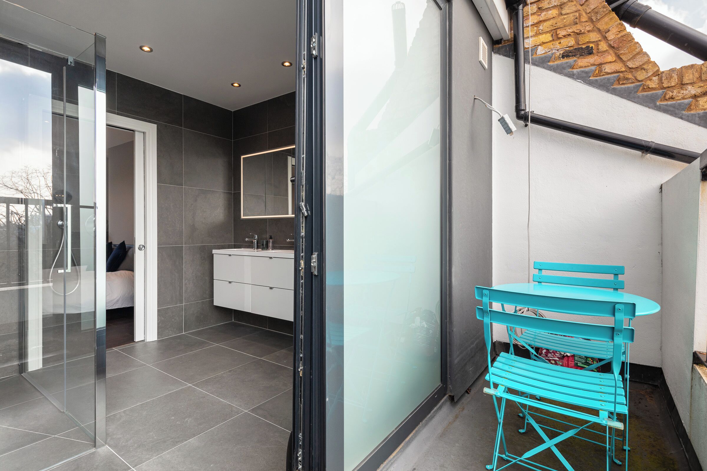 Een moderne badkamer met een glazen douchecabine, een wit wastafelmeubel en een spiegel.