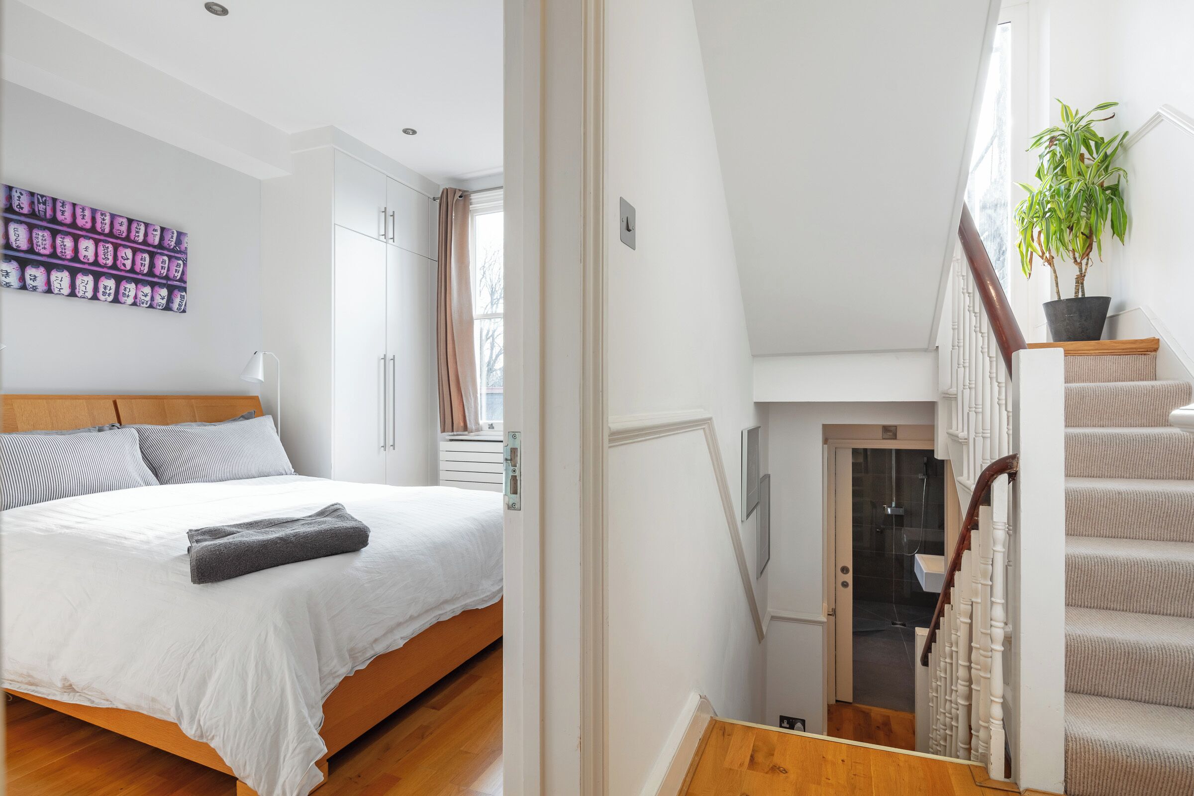 Ein Schlafzimmer mit einem Bett, einem Nachttisch, einem Fenster und einer Treppe zu einer oberen Etage.