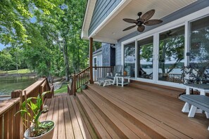 Eine Holzterrasse mit Sitzgelegenheiten im Freien, einem Deckenventilator und Blick auf einen See.