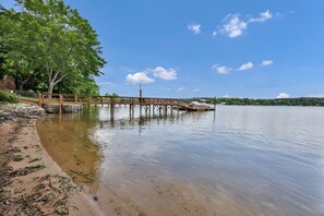 A wooden pier extending into calm water with a sandy beach on one side and trees in the background. - Sunset Cove @ Wateree- 2-bedrooms, 2-bathrooms, near Wateree Creek Landing (Winnsboro)