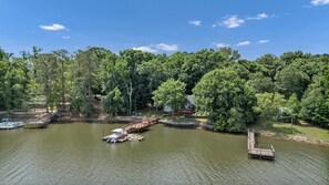 Um imóvel à beira do lago com um píer, um barco e uma ponte de madeira que liga à margem.