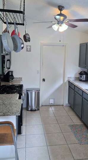 A kitchen with a gas stove, a trash bin, a ceiling fan, and cabinets. - Viera Home 3bed 2bath only 5min to Zoo pet-friendly (Melbourne)
