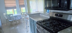 A kitchen with a gas stove, a microwave, and a dining area with a table and chairs. - Viera Home 3bed 2bath only 5min to Zoo pet-friendly (Melbourne)