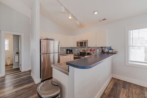 A modern kitchen with a stainless steel refrigerator, a microwave, and a built-in oven. - JL #061 E Z Livin - Hot Tub - Close to beach (Kill Devil Hills)
