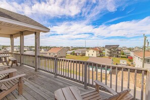 A wooden deck with outdoor seating, overlooking a residential area with houses and a clear sky. - JL #313 Sea Bass - Hot Tub - Game Room - Close to Beach (Kill Devil Hills)