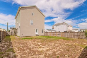 A two-story residential building with a front yard and a wooden fence. - JL #313 Sea Bass - Hot Tub - Game Room - Close to Beach (Kill Devil Hills)