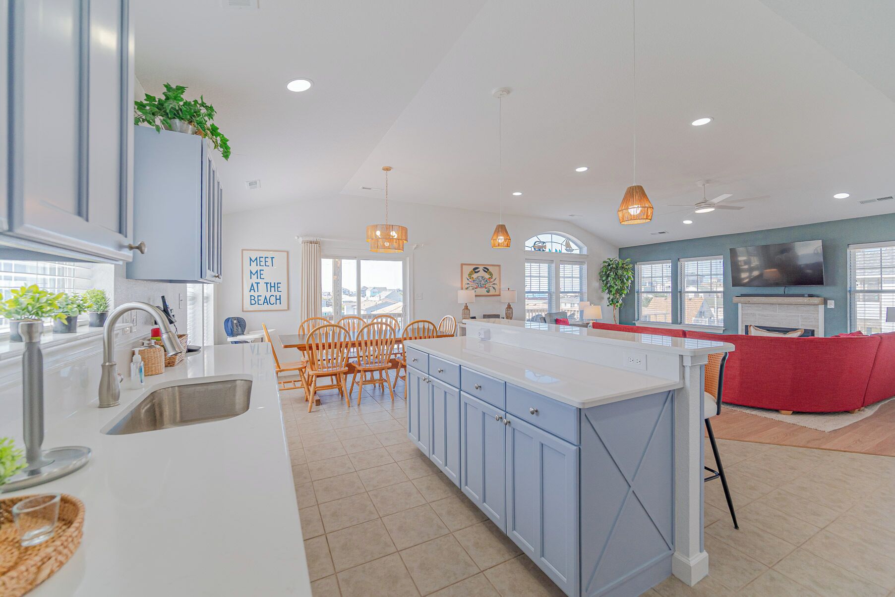 A modern kitchen with a central island, dining area with chairs, and a living space with a TV.