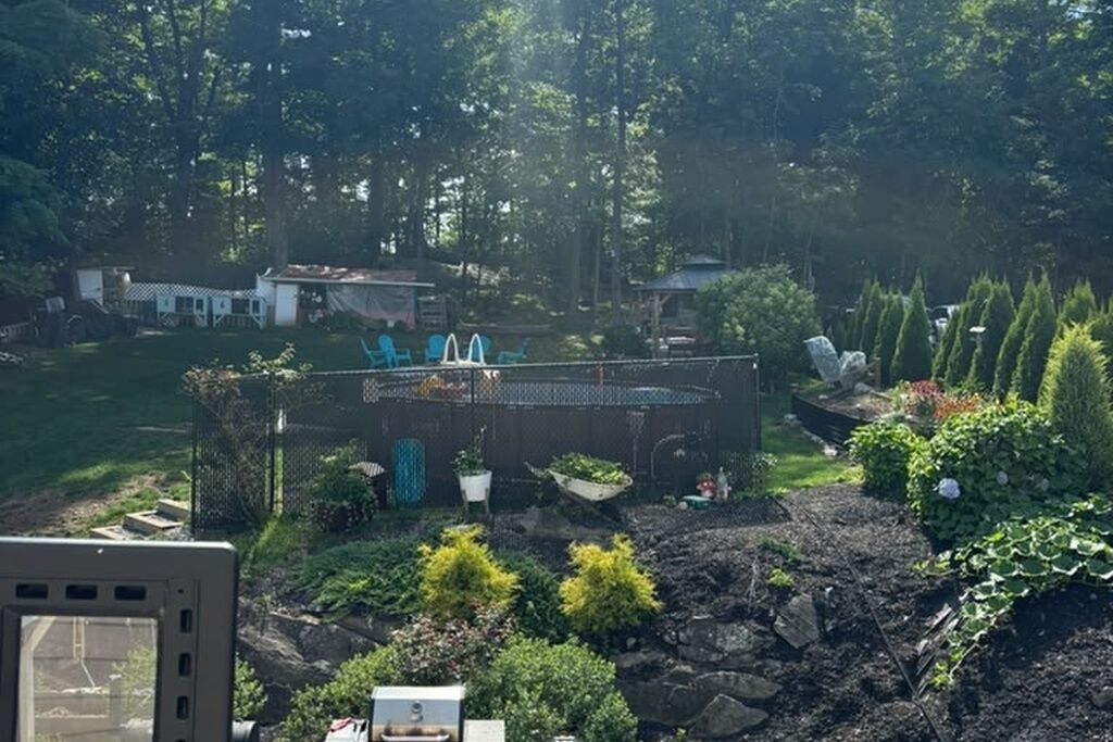 A garden with a barbecue area, a fenced play area, and various plants.