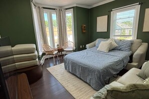 A bedroom with a bed, two chairs, a sofa, and a window with curtains. - SAGE Boutique Retreat • Sleeps 6 (Burrillville)