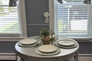 A dining table set with plates and a potted plant. - SAGE Boutique Retreat • Sleeps 6 (Burrillville)