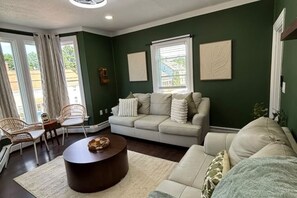 A living room with a sofa, two chairs, a coffee table, and artwork on the walls. - SAGE Boutique Retreat • Sleeps 6 (Burrillville)