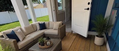 Un espacio al aire libre con patio, un sofá seccional, una mesa de centro y plantas en macetas.