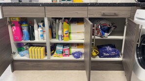 Eine Küche mit eingebauter Waschmaschine, Regalen voller Reinigungsmittel und einem Schrank für Toilettenartikel.