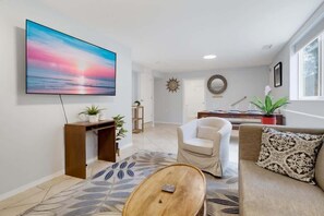 Ein Wohnzimmer mit Flachbildfernseher, einer Couch, einem Couchtisch und einem Teppich mit Muster.