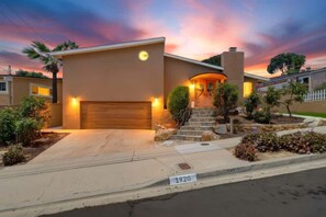 A modern two-story house with a garage, a well-maintained front yard, and a street address sign. - Bay Park Vacation House (San Diego)