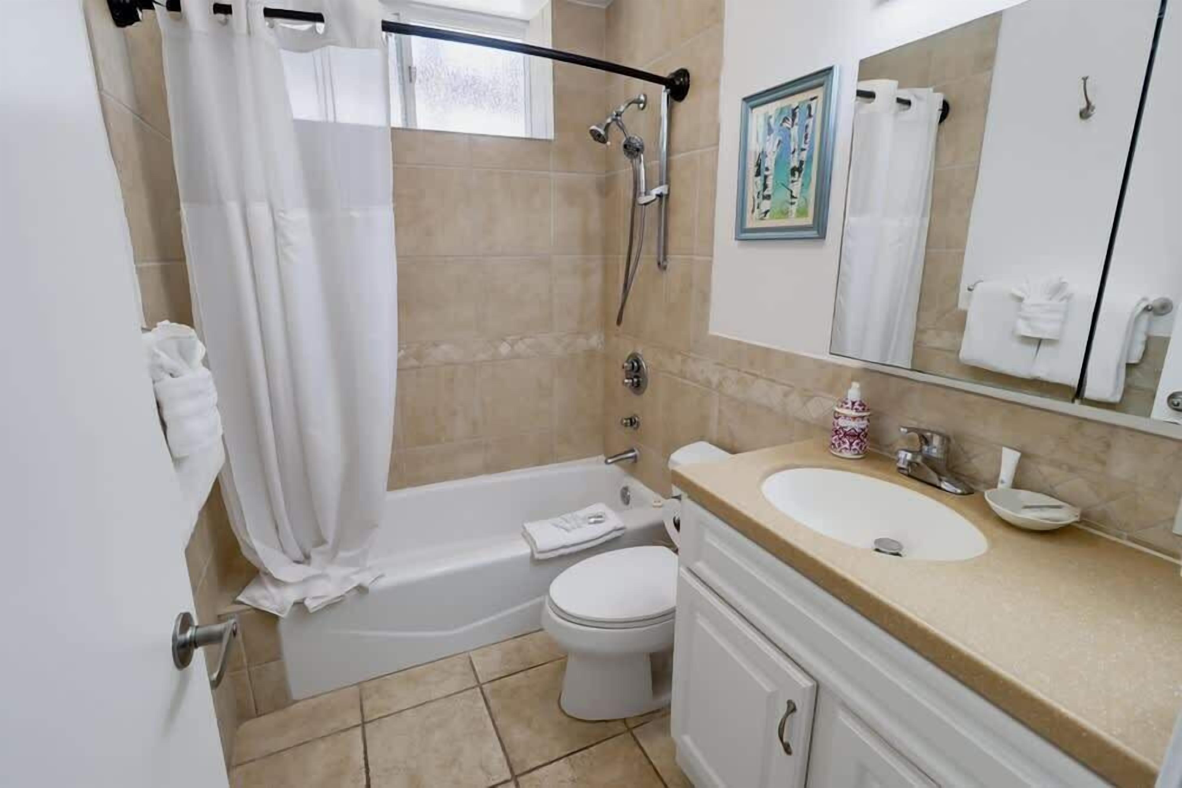 A bathroom with a bathtub, toilet, sink, and a shower area.