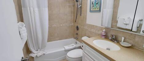 A bathroom with a bathtub, toilet, sink, and a shower area.