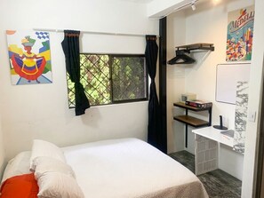 A bedroom with a bed, a window with curtains, a desk with a chair, and a wall-mounted shelf. - Prado Centro #2 Luxury Suite - Jacuzzi & Balcony (Medellín)