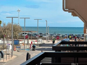 Een kustweg met uitzicht op zee, een parkeerplaats en een voetgangersoversteek.