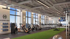 Een sportschool met trainingsapparatuur, grote ramen en stadszicht.