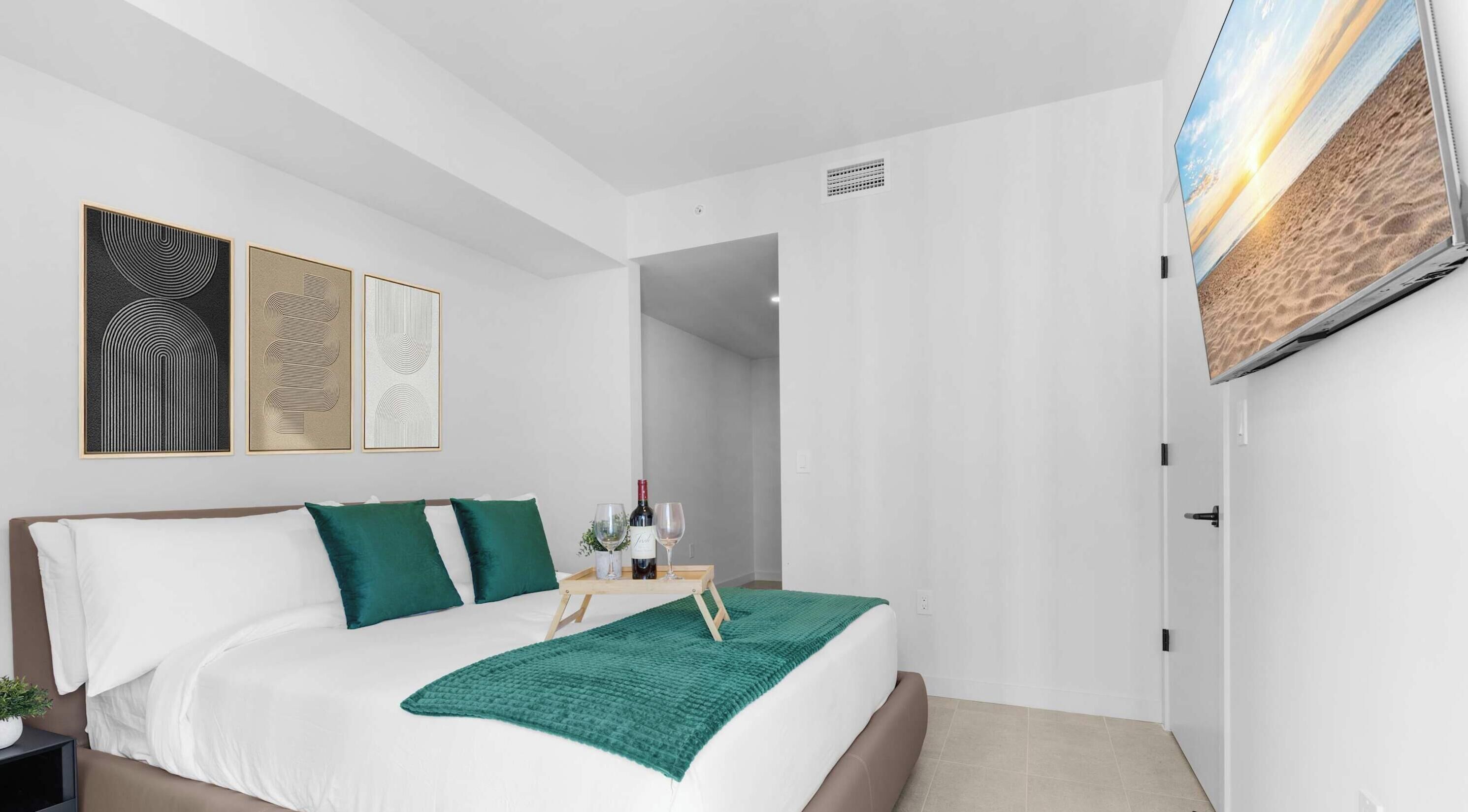 A modern bedroom with a bed, a TV mounted on the wall, and artwork on the wall.