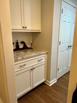 A kitchen with white cabinets, a granite countertop, and a wooden floor.