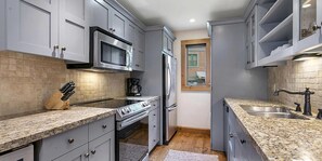 A compact kitchen with grey cabinets, a stainless steel refrigerator, a microwave, and a coffee maker. - Remodeled  East Vail Condo w/ Creekside Views, Free Shuttle Access!! (Vail)